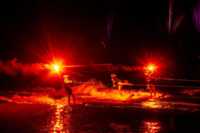 Wasserskiläufer bei Nacht, beleuchtet mit Bengalo-Fackeln